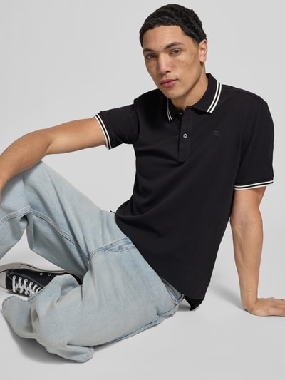 Männermodel trägt Slim Fit Poloshirt mit Logo-Stitching Modell 'Dunda' von G-Star Raw, Baumwoll-Mix, Polokragen, Ganzkörperansicht von vorne.