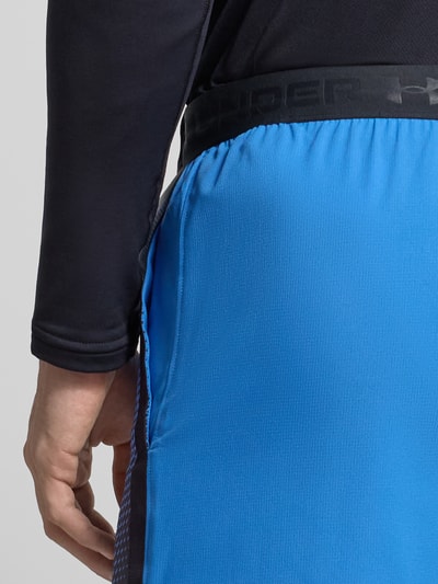 Mannenmodel draagt Regular Fit Shorts met Logo-Detail van Under Armour, blauw met elastische logoband, model 'Vanish Graphic', detailopname heup.