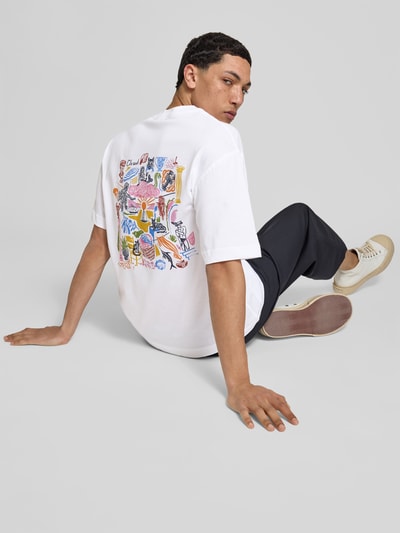 Männermodel trägt Regular Fit T-Shirt aus reiner Baumwolle von Closed mit Label-Print, weiß, buntes Rückenmuster, Kurzarm, Ganzkörperansicht Rückansicht.