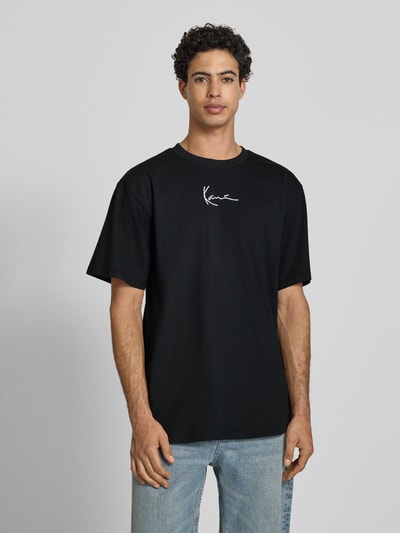 Męski model nosi T-Shirt mit Label-Stitching und Rundhalsausschnitt von KARL KANI, czarny, czysta bawełna, oversized, przód, długość pleców w rozmiarze M: 77 cm, prosty krój, faktura gładka, widok na całą sylwetkę z przodu