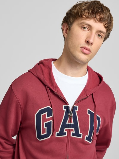 Männermodel trägt Sweatjacke mit Logo und Känguru-Tasche von GAP in Rot, Baumwoll-Mix, Regular-Fit, Nahaufnahme Oberkörper.