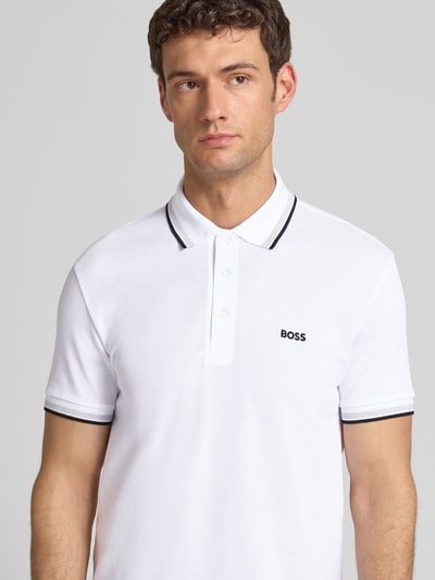 Männermodel trägt Regular Fit Poloshirt mit Label-Stitching Modell 'Paddy' von BOSS, weiße Baumwolle mit Kontrastdetails, Nahaufnahme Oberkörper.