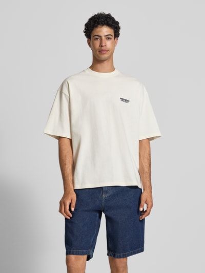 Männermodel trägt T-Shirt mit Rundhalsausschnitt und Logo-Print von REVIEW in Creme, Modern Fit, Reine Baumwolle, Rückenlänge 68 cm, Ganzkörperansicht von vorne.