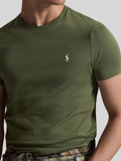 Männermodel trägt Regular Fit T-Shirt aus reiner Baumwolle von Polo Ralph Lauren in Olivgrün mit Logo-Stitching, Nahaufnahme Oberkörper.