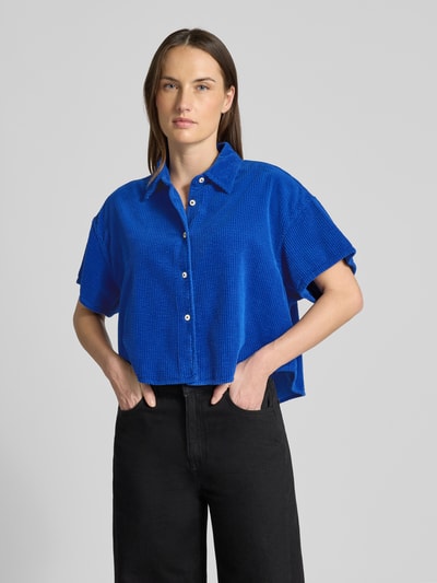 Modelka nosi Cropped Hemdbluse mit Knopfleiste Modell 'PADOW' von American Vintage, czysta bawełna, luźny krój, krótki rękaw, kolor niebieski, widok na cały przód górnej części ciała.