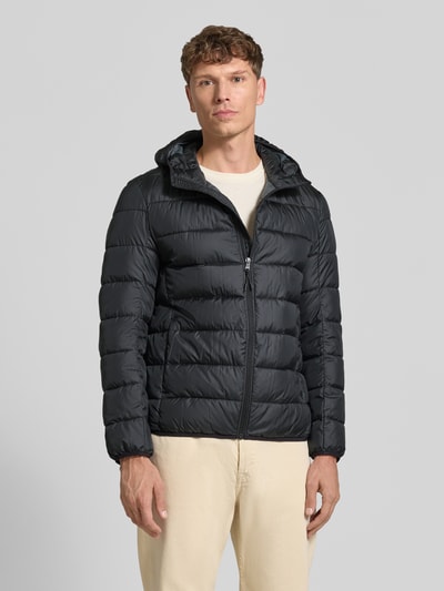 Męski model nosi Steppjacke mit Kapuze und Reißverschluss von MCNEAL w kolorze czarnym, faktura pikowana, krój regular fit, kaptur, zamek błyskawiczny, kieszenie boczne, długość tyłu w rozmiarze M 70 cm, szerokość ramion w rozmiarze M 46 cm, szerokość w klatce piersiowej w rozmiarze M 54 cm, długość rękawa w rozmiarze M 63 cm, pełny widok z przodu.