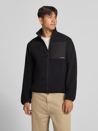 Männermodel trägt schwarze Fleecejacke mit Zweiwege-Reißverschluss Modell 'MASON' von JACK & JONES, Regular Fit, Ganzkörperansicht von vorne.