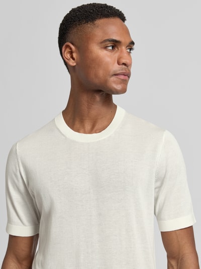 Męski model nosi Strickshirt mit Rundhalsausschnitt und 1/2-Arm von OLYMP Level Five, mieszanka bawełny i lyocellu, krój regular fit, okrągły dekolt, rękaw o dł. 1/2, długość tyłu w rozmiarze M: 67 cm, jasny kolor, gładka tekstura, zbliżenie na górną część ciała