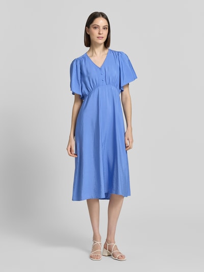 Frauenmodel trägt Midikleid aus Viskose-Mix mit V-Ausschnitt Modell 'Aniva' von ICHI, taillierte Passform, Kurzärmelig, Knopfleiste, leuchtendes Blau mit sanftem Glanz, leichte Textur, Ganzkörperansicht von vorne. Rückenlänge bei Größe 36: 116 cm, Brustweite 34 cm, Ärmellänge 26 cm.