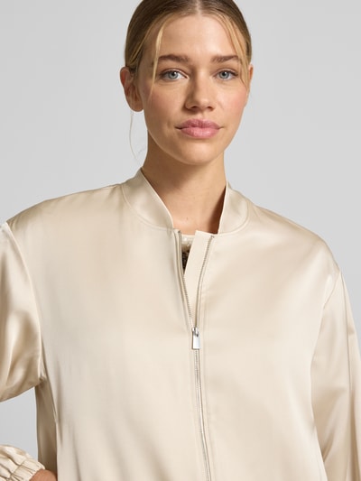 Kobiece modelka nosi Blouson mit Stehkragen und Reißverschluss od comma, jasny beż, materiał-mix z dodatkiem wiskozy, krój regular fit, detaliczny zamek błyskawiczny, długość tyłu w rozmiarze 36: 52 cm, szerokość w rozmiarze 36: 50 cm, długość rękawa w rozmiarze 36: 57 cm, gładka tekstura, zbliżenie na górną część ciała.