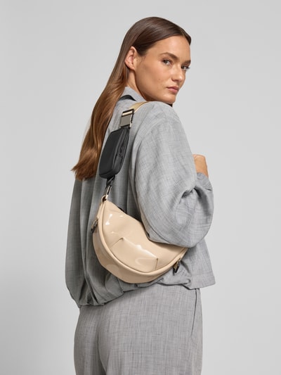 Frauenmodel trägt Handtasche mit Label-Detail Modell 'VALERA' von Rains in Beige mit verstellbarem Schulterriemen, Hauptfach mit Reißverschluss, Ganzkörperansicht Rückansicht. Breite 22 cm, Länge 14 cm, Tiefe 13 cm, Länge Schulterriemen 78 cm.