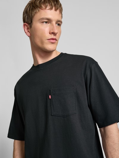 Männermodel trägt T-Shirt mit Brusttasche und Label-Detail von Levi's®, reine Baumwolle, gerader Schnitt, Nahaufnahme Oberkörper.