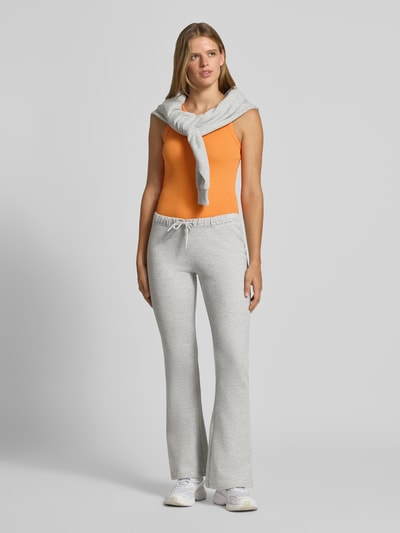 Frauenmodel trägt Flared Sweatpants aus reiner Baumwolle von REVIEW in Hellgrau mit elastischem Bund und Eingrifftaschen, Ganzkörperansicht von vorne.