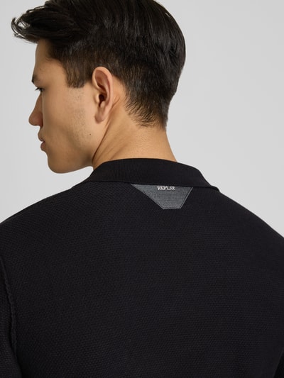 Männermodel trägt Slim Fit Poloshirt in Strick-Optik von Replay in Schwarz, Struktur sichtbar, Detailaufnahme Rückenansicht. Reine Baumwolle.