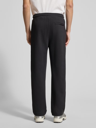 Männermodel trägt Regular Fit Sweatpants aus katoenmix Modell 'JT_Member Hurley' van BOSS Green, uni, label stitching, elastische tailleband, fixeerde vouwen, zijzakken, decoratieve achterzak, sweatmateriaal, Ganzkörperansicht Rückansicht.