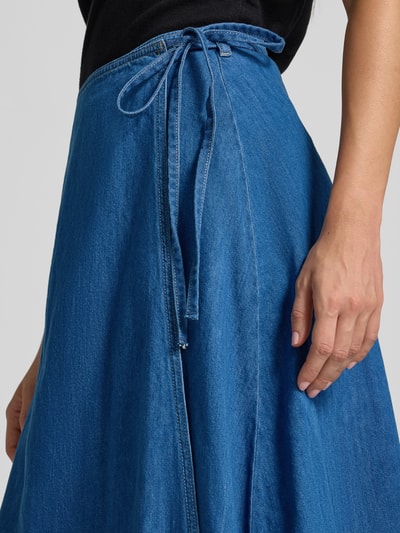 Frauenmodel trägt Ausgestellter Midi-Rock von s.Oliver RED LABEL in leuchtendem Blau mit Bindegürtel, Nahaufnahme Hüfte und Hand.