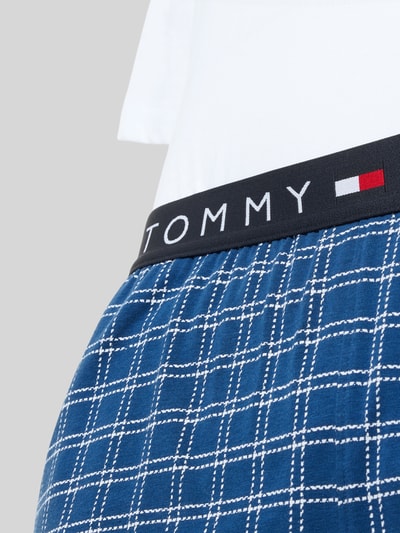 Männermodel trägt Regular Fit Pyjama aus bawełnianej mieszanki von Tommy Hilfiger, góra: jednokolorowa, dół: wzór w kratę, wyhaftowane logo, elastyczny pas z logo, komplet, wpuszczane kieszenie, okrągły dekolt, krótki rękaw, zdjęcie: detailaufnahme pasa i wzoru spodenek.