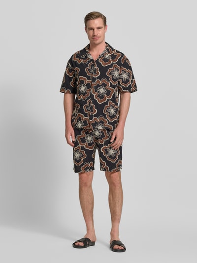 Męski model prezentuje Straight Fit Shorts mit floralem Allover-Stitching od Antony Morato w czerni z beżowo-brązowym haftem, czysta bawełna, elastyczny pas ze sznurkiem, kieszeń z tyłu, szerokość w rozmiarze 50: 45 cm, długość wewnętrzna nogawki w rozmiarze 50: 22 cm, widok całej sylwetki z przodu.