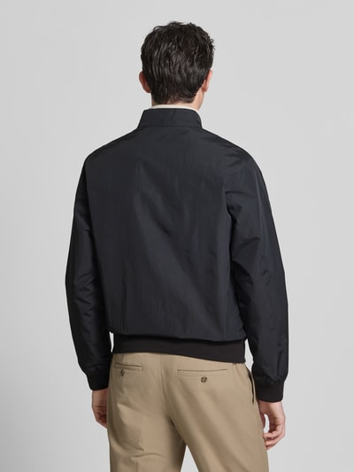 Männermodel trägt Regular Fit Blouson mit Stehkragen Modell 'Royston' von Barbour, look: effen, lange mouw, rompzoom en mouwboord, zij-steekzakken, labelopschrift, luchtgaten, tweewegritssluiting, binnenzak, geheel lichaamsaanzicht achteraan.