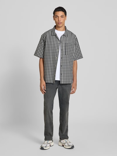 Mężczyznamodel nosi Slim Fit Jeans mit Lyocell-Anteil Modell 'Clark' von JACK & JONES w kolorze ciemnoszarym, mieszanka bawełny i lyocellu, 5 kieszeni, zapięcie na guzik i zamek błyskawiczny, Szerokość w rozmiarze 32/32: 34 cm, Długość wewnętrzna nogawki w rozmiarze 32/32: 78 cm, Ganzkörperansicht von vorne