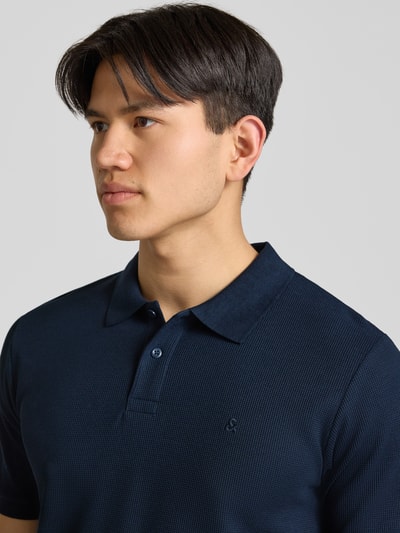 Männermodel trägt Regular Fit Poloshirt mit Strukturmuster Modell 'AUSTIN' von Jack & Jones im Material-Mix, Nahaufnahme Oberkörper.