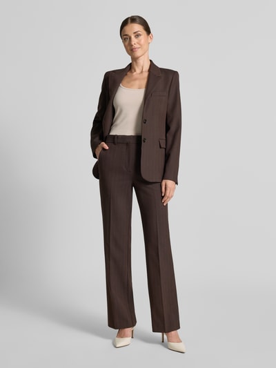 Frauenmodel trägt Flared Anzughose mit Viskose-Anteil Modell 'BERGEN' von MANGO in Braun, glatte Textur, Ganzkörperansicht von vorne.