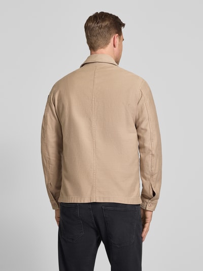 Męski model nosi Regular Fit Hemdjacke mit Brusttaschen Modell 'Goodale' od Blauer Usa, beżowa bawełniana kurtka koszulowa z kieszeniami, widok całej sylwetki od tyłu, długość pleców w rozmiarze M: 72 cm, szerokość ramion w rozmiarze M: 52 cm, szerokość klatki piersiowej w rozmiarze M: 55 cm, długość rękawa w rozmiarze M: 68 cm.