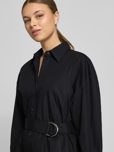Frauenmodel trägt tailliertes Hemdblusenkleid aus reiner Baumwolle Modell 'KUMIRA' von HUGO in Schwarz, Nahaufnahme Oberkörper. Unifarbene Optik, Knopfleiste, Taillengürtel.