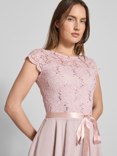 Kobiece model prezentuje Cocktailkleid mit Spitzenbesatz und Bindegürtel von SWING, różowy materiał, koronka, błyszczące cekiny, widok z przodu, zbliżenie na górę sukienki.