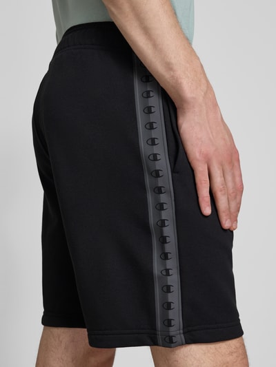 Männermodel trägt Shorts mit Logo und elastischem Bund von CHAMPION in Schwarz, Baumwoll-Mix, Regular Fit, Nahaufnahme Oberschenkel.