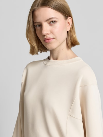 Vrouwenmodel draagt Sweatshirt mit Rundhalsausschnitt und 3/4-Arm van comma in crème, relaxed fit, katoen-elastaan mix, close-up bovenlichaam.