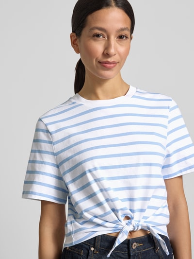 Frauenmodel trägt T-Shirt im Allover-Look mit Knotendetail von Rich & Royal aus Reiner Bio-Baumwolle, Regular-Fit, Rundhalsausschnitt, Rückenlänge 48 cm, Nahaufnahme Oberkörper.