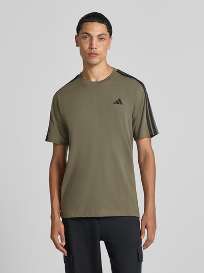 Männermodel trägt Regular Fit T-Shirt aus reiner Baumwolle Modell 'M 3S SJ LC T' von adidas, olivgrün mit schwarzen Details, Herren T-Shirt von adidas Sportswear, Ganzkörperansicht von vorne.
