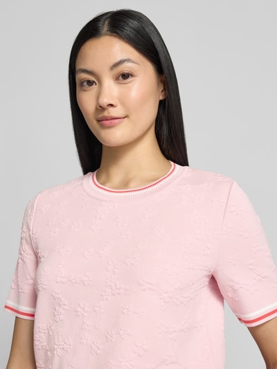 Kobiece model prezentuje Regular Fit T-Shirt aus Viskose-Mix von Marc Cain, różowy, kwiatowy wzór na całej powierzchni, okrągły dekolt, mieszanka wiskozy i bawełny, krótki rękaw, długość tyłu w rozmiarze 36: 56 cm, długość rękawa: 25 cm, zbliżenie na górną część ciała.