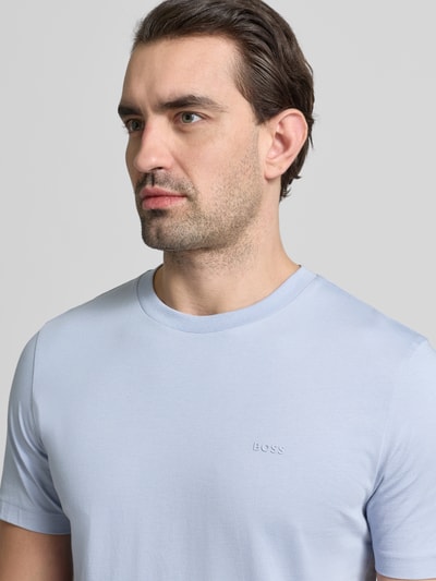 Männermodel trägt Regular Fit T-Shirt aus reiner Baumwolle Modell 'THOMPSON' von BOSS in Hellblau, Label Print, Nahaufnahme Oberkörper.