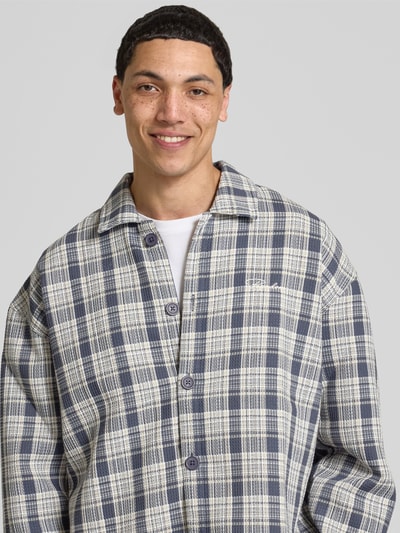 Männermodel trägt Relaxed Fit Freizeithemd mit Kentkragen und Label-Stitching von Pegador mit Strukturmuster, Nahaufnahme Oberkörper.
