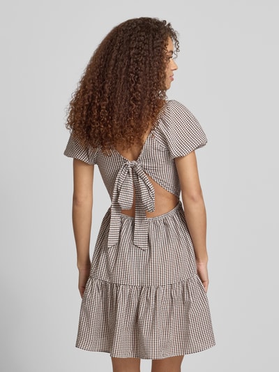 Frauenmodel trägt Knielanges Kleid mit Karree-Ausschnitt Modell 'ELIZA' von Noisy May im Material-Mix, A-Linie, kariertes Muster, Rückenansicht.