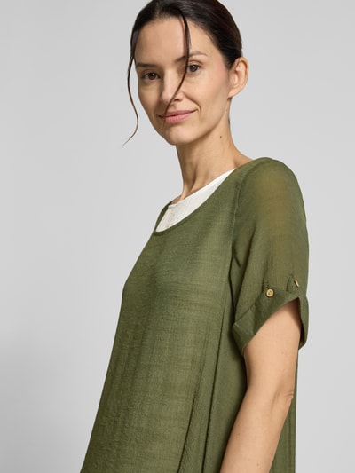 Frauenmodel trägt knielanges Kleid aus Viskose-Mix von Apricot in Olive, leicht strukturierte Oberfläche, Rundhalsausschnitt, Nahaufnahme Oberkörper.