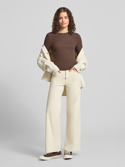 Frauenmodel trägt Slim Fit Langarmshirt aus Baumwoll-Mix Modell 'VAL' von ONLY in Braun zu heller Hose, Damen Langarmshirt, Ganzkörperansicht von vorne.