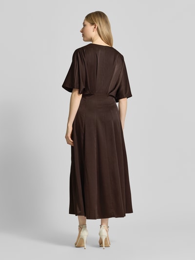 Frauenmodel trägt Midikleid mit V-Ausschnitt Modell 'VIANNA' von Copenhagen Muse, braun, tailliert, Ganzkörperansicht Rückansicht.