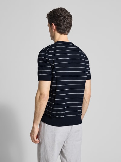 Männermodel trägt Regular Fit T-Shirt aus Baumwoll-Kaschmir-Mix Modell 'KANACHO' von BOSS Orange, schwarz mit weißen Streifen, Strickoptik, Ganzkörperansicht Rückansicht.