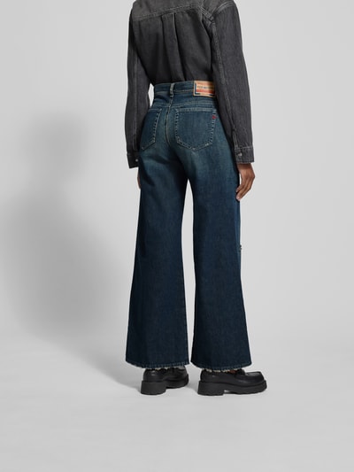 Frauenmodel trägt Wide Fit Jeans mit 5-Pocket-Design von Diesel aus Baumwoll-Lyocell-Mix in Dunkelblau, Label-Detail, lockerer Schnitt, Ganzkörperansicht Rückansicht.