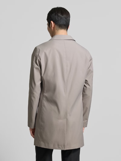 Männermodel trägt Mantel mit Knopfleiste von MCNEAL in heller Beige-Farbe, lockerer Schnitt, glatte Oberfläche, Ganzkörperansicht Rückansicht.