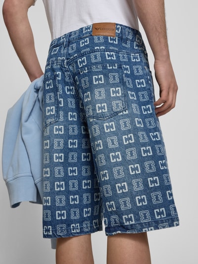 Männermodel trägt Straight Fit Jeans in Denim-Optik mit Allover-Logo-Print von COLUCCI, 5-Pocket-Design, Rückansicht, Nahaufnahme Oberschenkel.