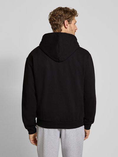 Männermodel trägt Relaxed Fit Hoodie aus katoenmix von Lacoste in zwart, effen stof, Heren sweatshirt, ganzkörperansicht rückansicht.