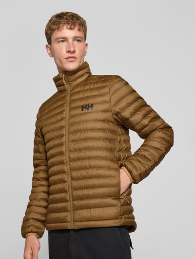 Männermodel trägt Steppjacke mit Label-Print von Helly Hansen in Braun, Stehkragen, elastische Ärmel, Nahaufnahme Oberkörper.