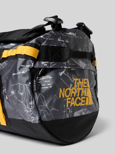 Produktfoto, Weekender mit Logo-Print von The North Face in Schwarz mit gelben Details, mattem Material, Hauptfach mit Reißverschluss, Reißverschlussfach, verstellbare Schulterriemen, Maße: Breite 50 cm, Länge 32 cm, Tiefe 30 cm, Schulterriemen 92 cm.