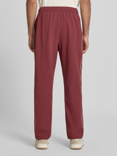 Männermodel trägt Trackpants mit Logo-Stitching Modell 'Seersucker' von Les Deux, Strukturmuster, Kontraststreifen, Ganzkörperansicht Rückansicht.