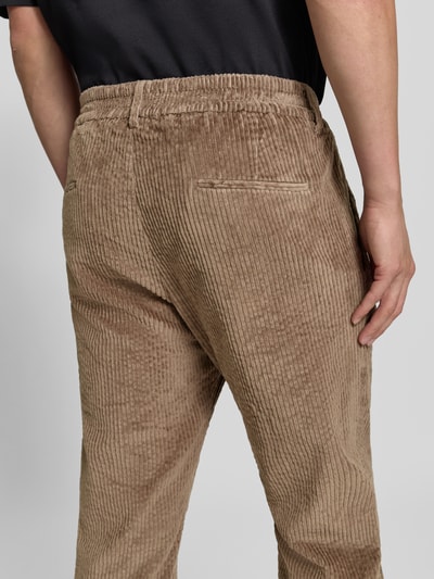 Männermodel trägt Straight Fit Hose aus Baumwoll-Mix Modell 'Chasy' von DRYKORN in Cord-Optik, Gesäßtaschen, Rückansicht, Nahaufnahme Oberschenkel, elastischer Bund.