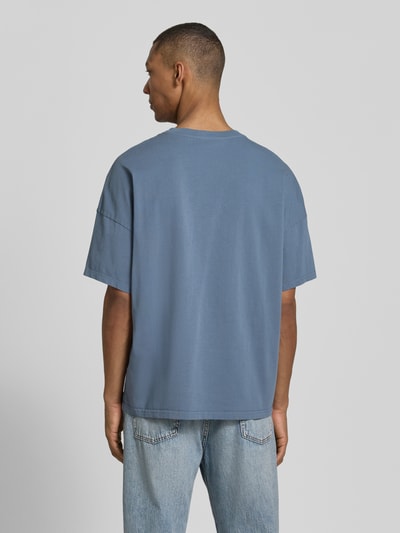 Männermodel trägt T-Shirt mit geripptem Rundhalsausschnitt Modell 'FIZVALLEY' von American Vintage, blaue Baumwolle, Loose Fit, Ganzkörperansicht Rückansicht.